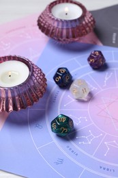 Zodiac wheels, astrology dices and burning candles on table, closeup