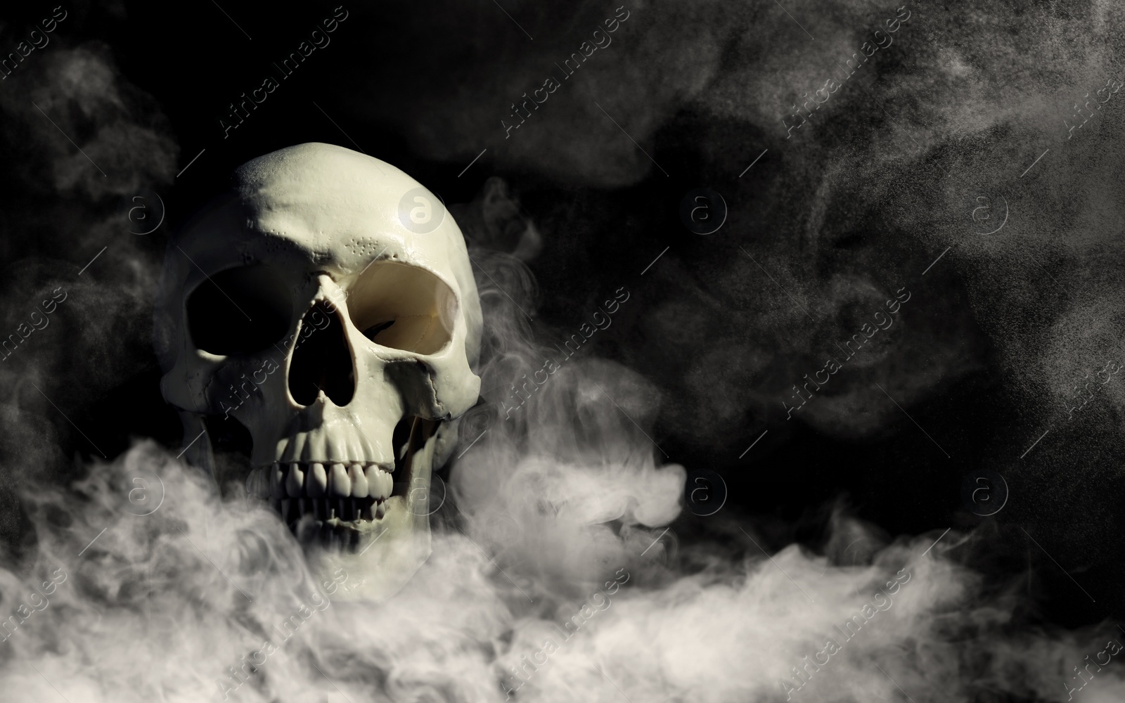 Image of Scary skull emerging from smoke in darkness