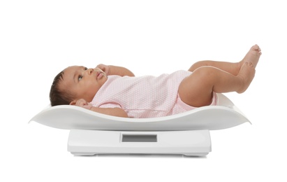 Photo of African-American baby lying on scales against white background