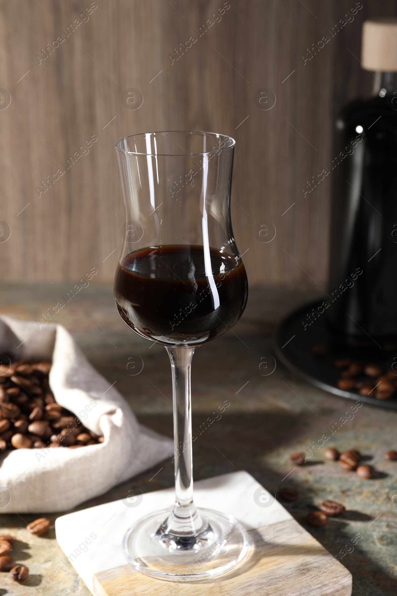 Photo of Glass of coffee liqueur and beans on textured table