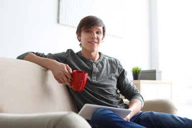 Photo of Portrait of young man drinking coffee on sofa