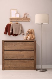 Photo of Children's room interior with stylish wooden furniture, baby clothes and lamp