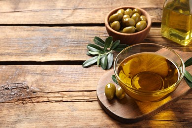 Photo of Fresh oil, ripe olives and green leaves on wooden table. Space for text