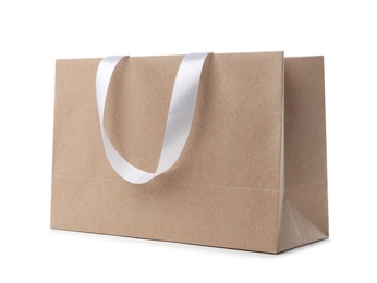 Paper shopping bag with ribbon handles on white background. Mockup for design