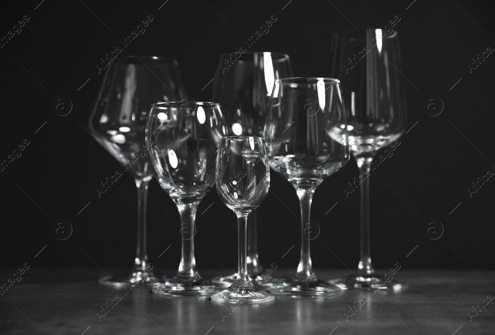 Photo of Set of bar glassware on table against dark background