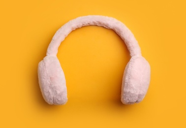 Stylish winter earmuffs on orange background, top view