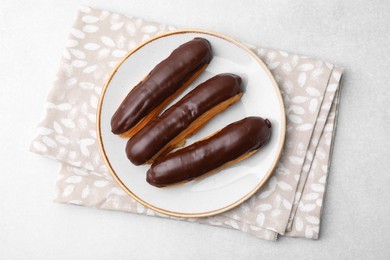 Photo of Delicious eclairs covered with chocolate on grey table, top view