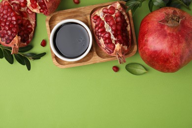 Photo of Flat lay composition with tasty pomegranate sauce and fruits on green table. Space for text