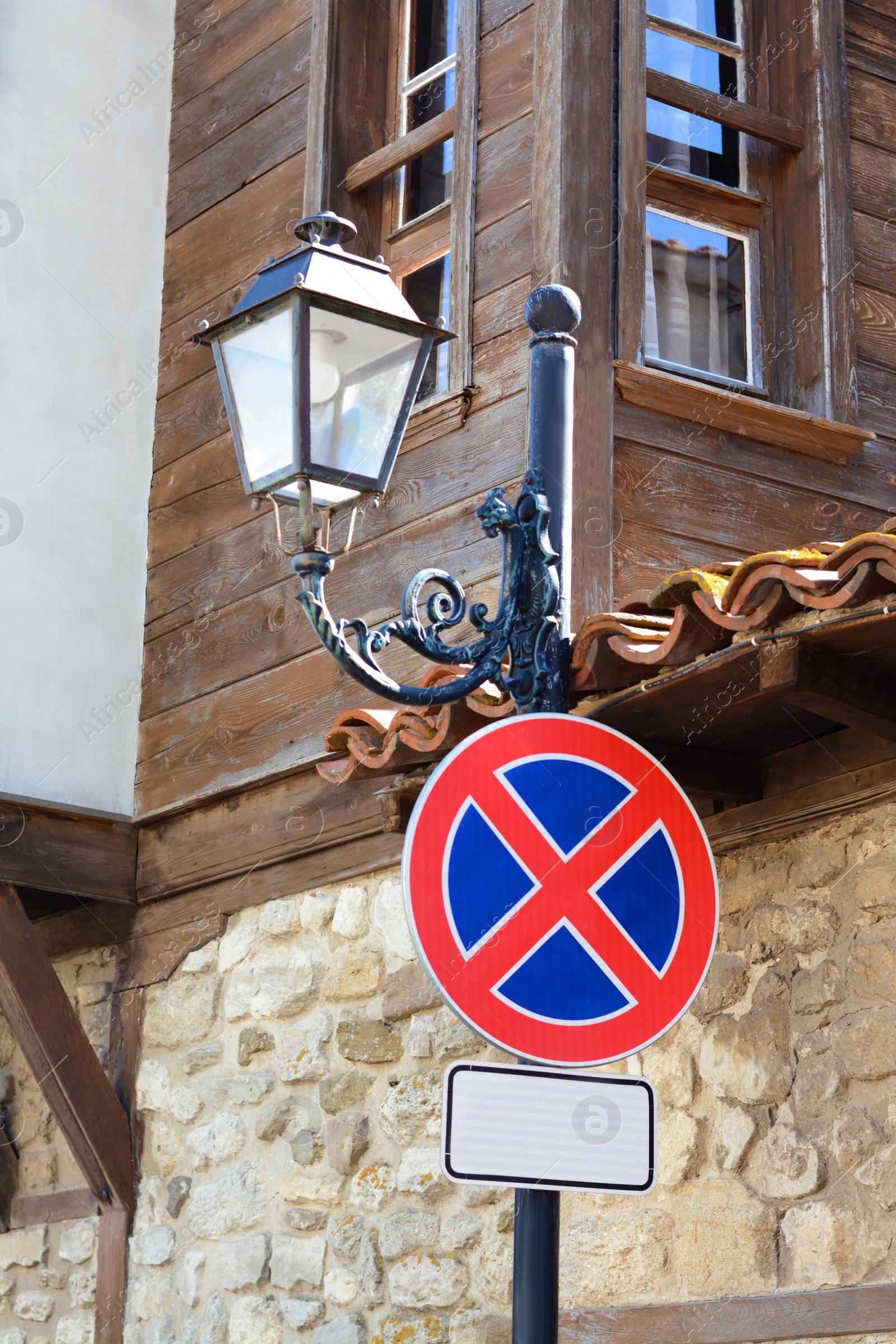 Photo of Traffic sign No Stopping on streetlight near building outdoors