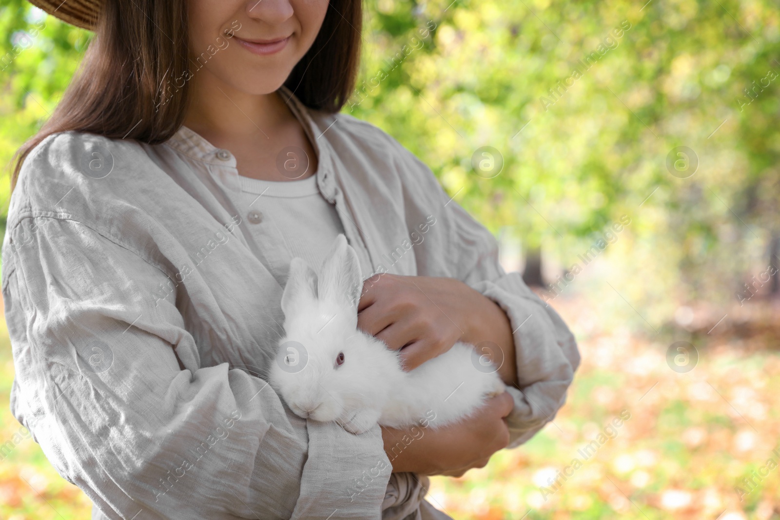 Photo of Woman holding cute white rabbit in park, closeup