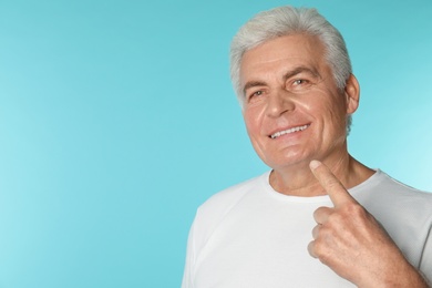 Photo of Mature man with healthy teeth on color background. Space for text