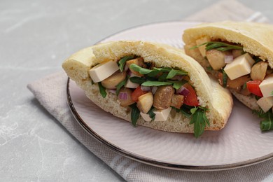 Photo of Delicious pita sandwiches with cheese, mushrooms tomatoes and arugula on light grey marble table
