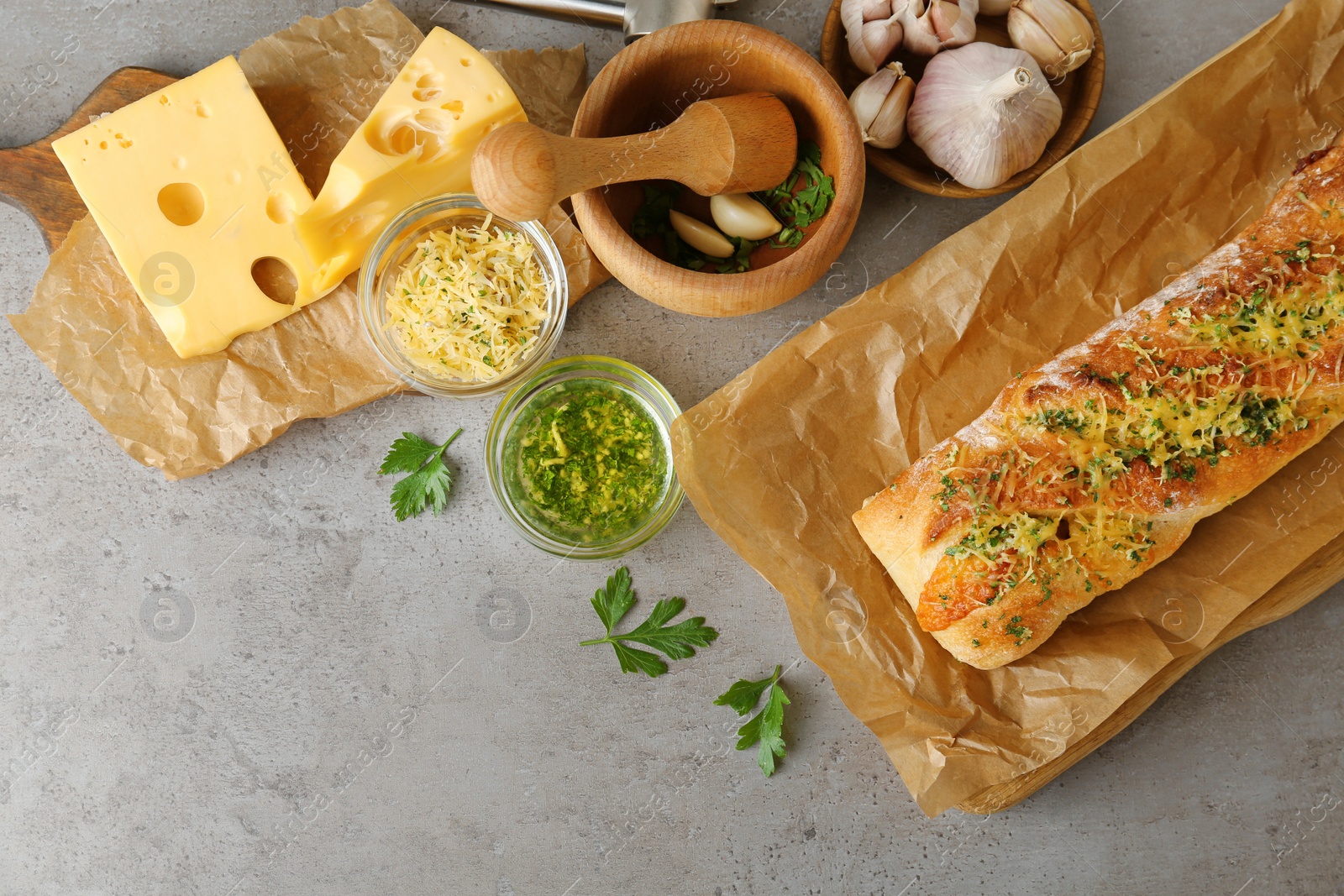 Photo of Tasty homemade garlic bread with cheese and herbs on grey table, flat lay