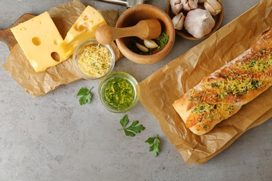 Photo of Tasty homemade garlic bread with cheese and herbs on grey table, flat lay