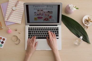Photo of Woman working with fashion blogger site on laptop at table, top view