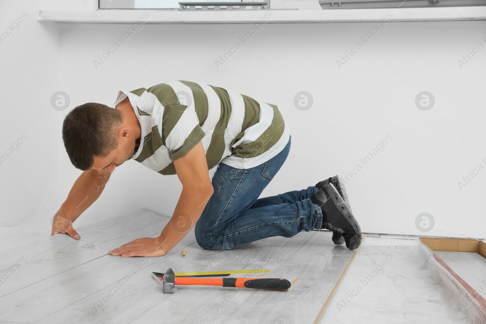 Photo of Professional worker installing new laminate flooring indoors