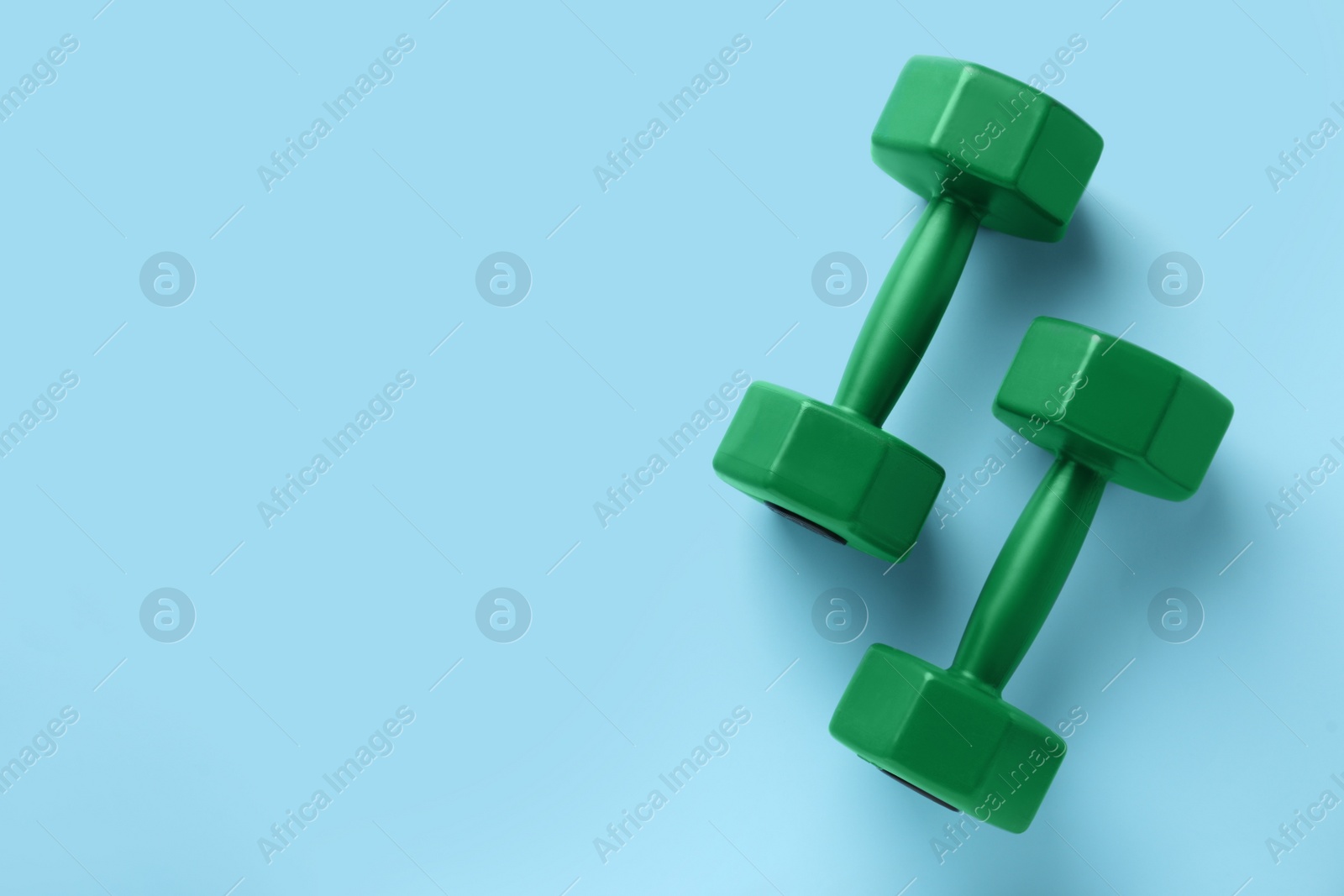 Photo of Stylish dumbbells on light blue background, flat lay. Space for text