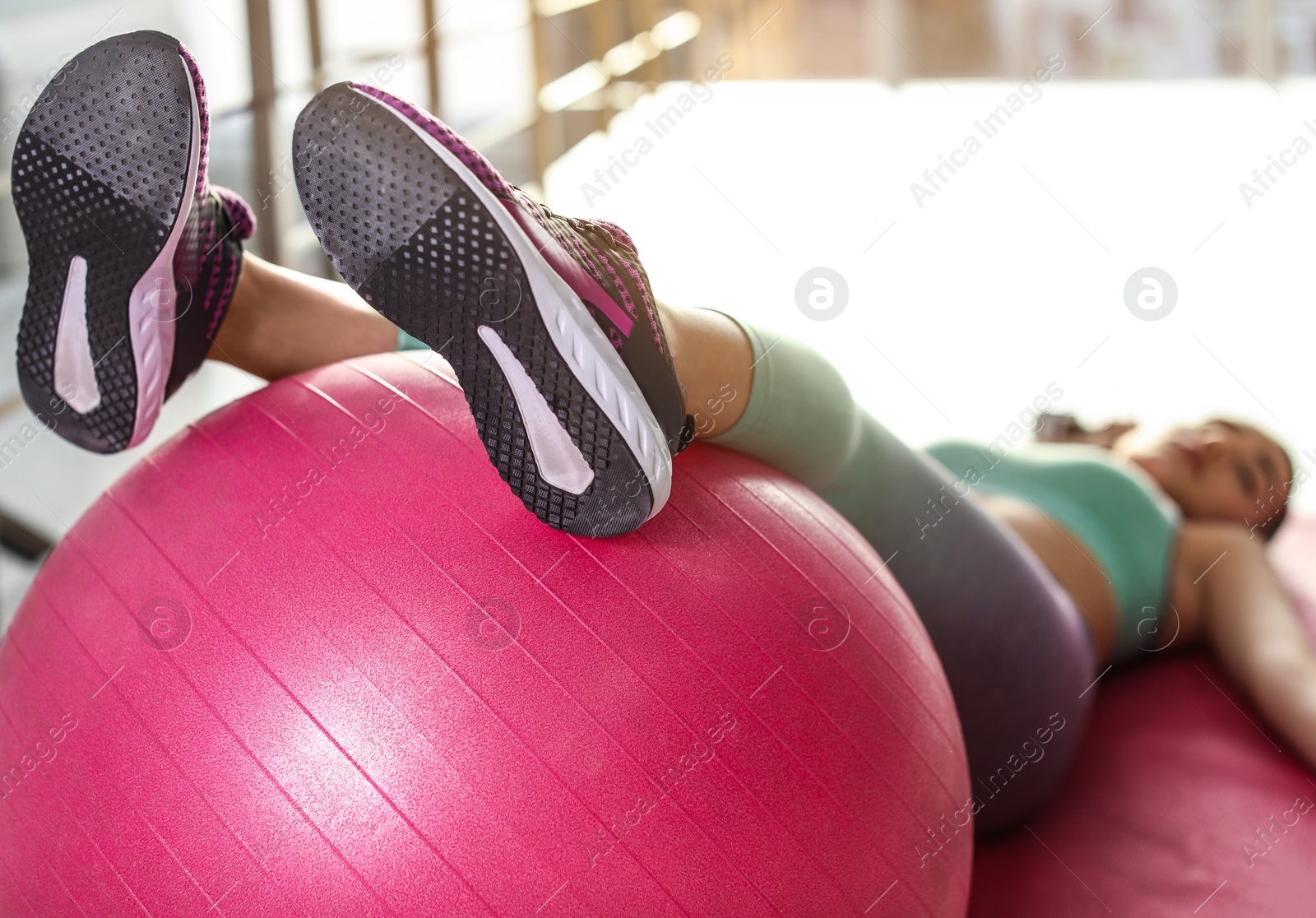 Photo of Lazy young woman with sport equipment on yoga mat indoors, focus on legs