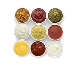 Many different sauces in bowls on white background, top view