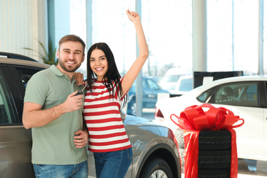 Photo of Happy couple with car key in modern auto dealership