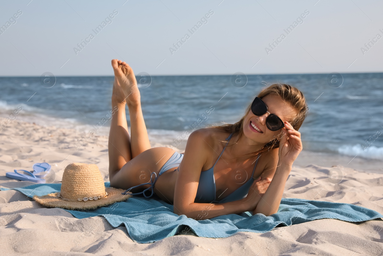 Photo of Attractive woman with sunglasses sunbathing on beach towel near sea