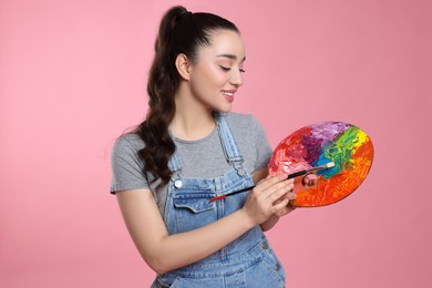 Photo of Woman with painting tools on pink background. Young artist