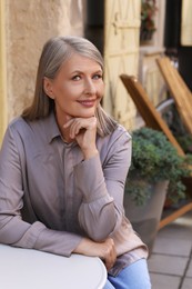Photo of Portrait of beautiful happy senior woman at table in outdoor cafe
