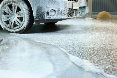 Modern automobile covered with foam at car wash