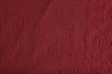 Crumpled dark red fabric as background, top view