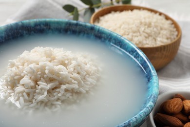 Photo of Bowl with rice soaked in water on table, closeup