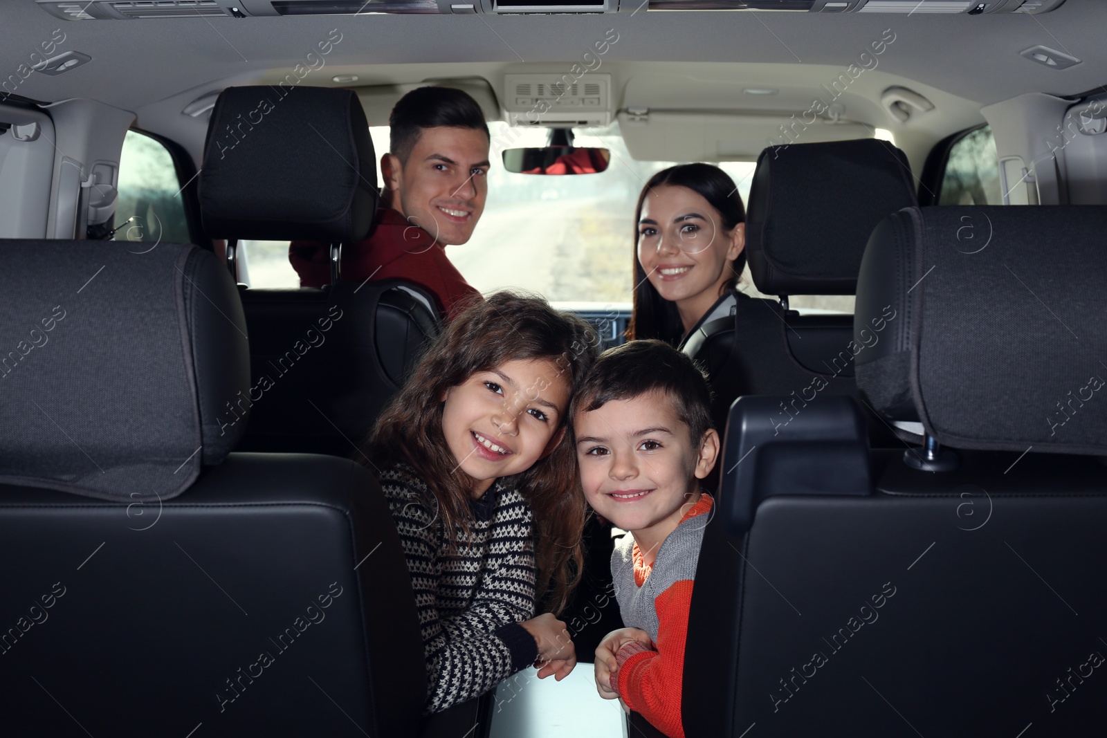 Photo of Happy family with little children inside modern car