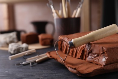 Photo of Clay and loop tool on dark gray wooden table in workshop, closeup