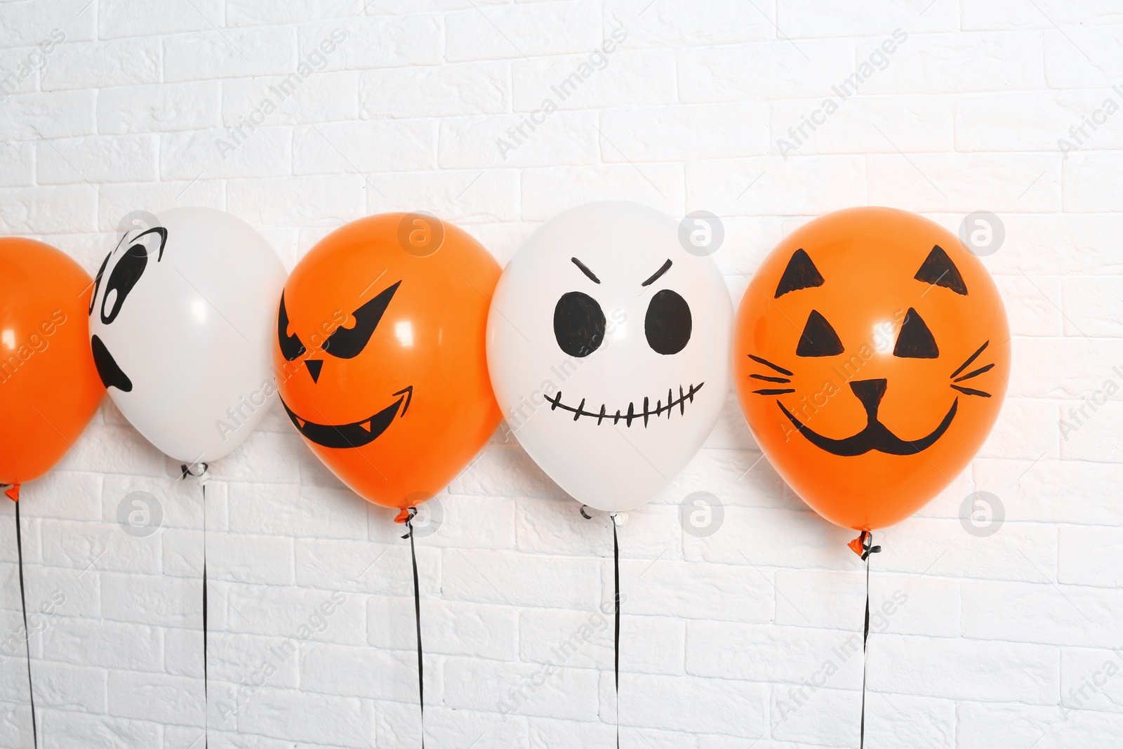 Photo of Color balloons for Halloween party against white brick wall