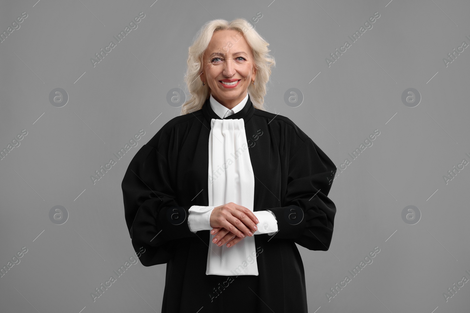 Photo of Smiling senior judge in court dress on grey background
