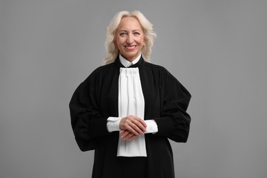 Photo of Smiling senior judge in court dress on grey background