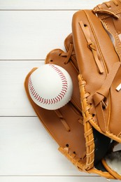 Photo of Leather baseball glove with ball on white wooden table, top view