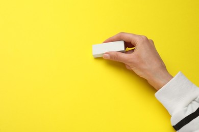 Photo of Woman erasing something on yellow background, closeup. Space for text