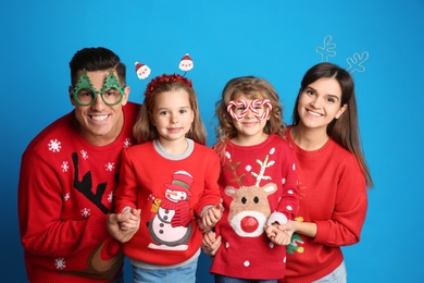 Photo of Family in Christmas sweaters and festive accessories on blue background