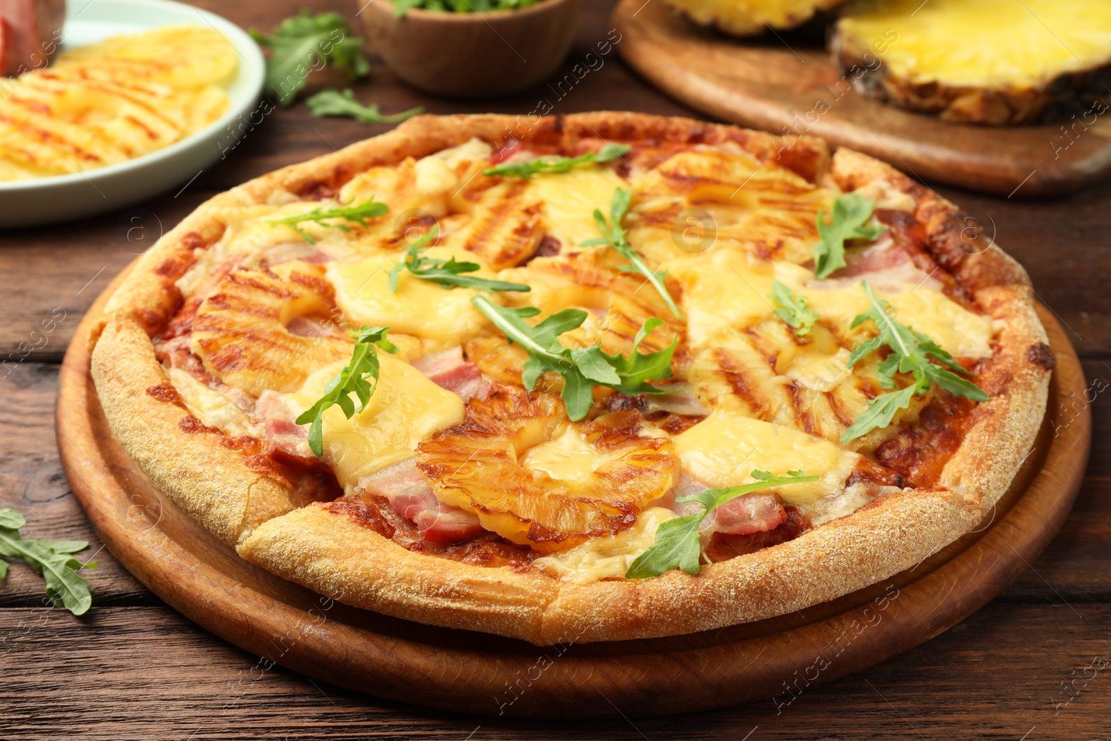 Photo of Delicious pineapple pizza with arugula on wooden table, closeup