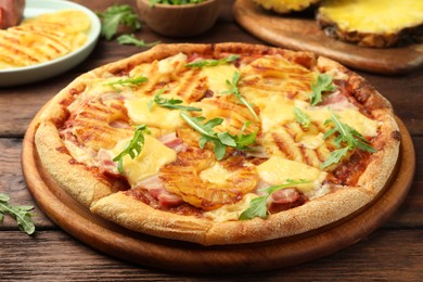Photo of Delicious pineapple pizza with arugula on wooden table, closeup