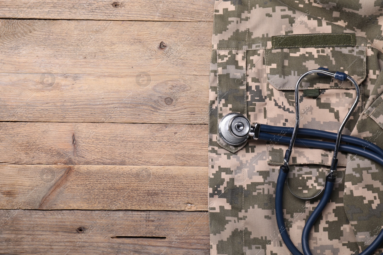 Photo of Stethoscope and military uniform on wooden background, top view. Space for text