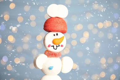 Photo of Funny snowman made of marshmallows against blurred festive lights, closeup. Space for text