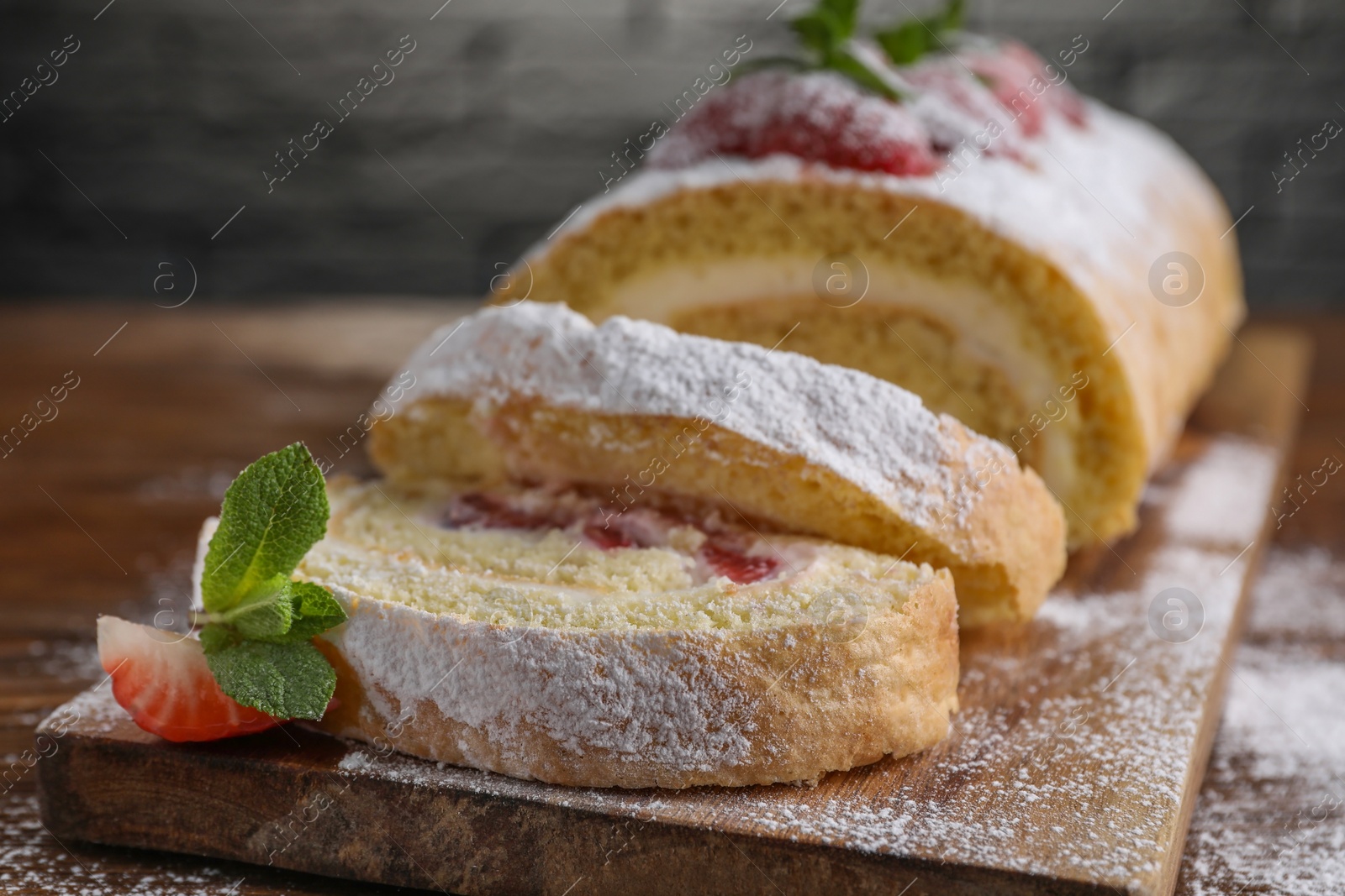 Photo of Pieces of delicious cake roll with strawberries and cream on table, closeup