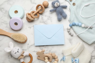 Photo of Baby shower party. Envelope surrounded by stuff for child on white marble background, flat lay