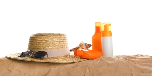 Different beach accessories on sand against white background