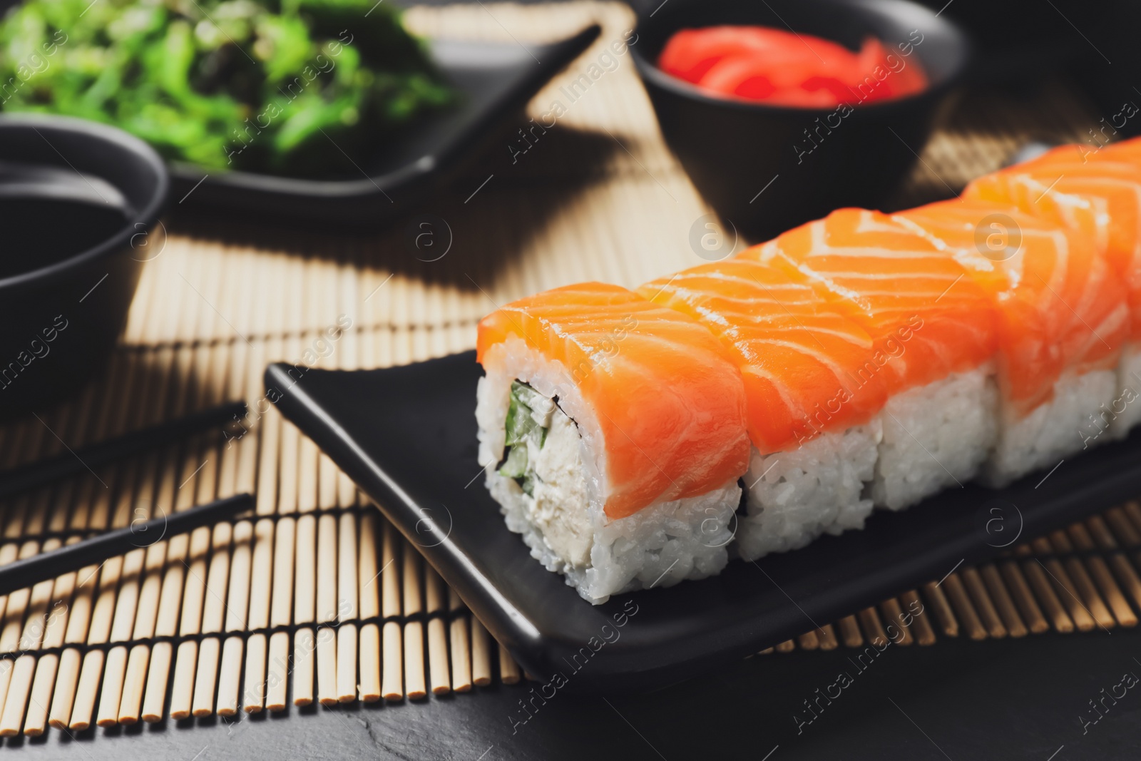 Photo of Tasty sushi rolls served on black table, closeup