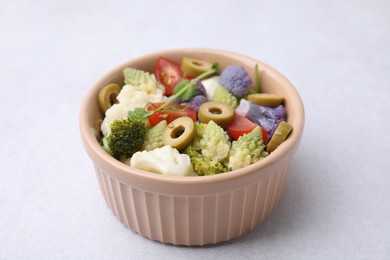 Photo of Delicious salad with cauliflower, tomato and olives on white table, closeup