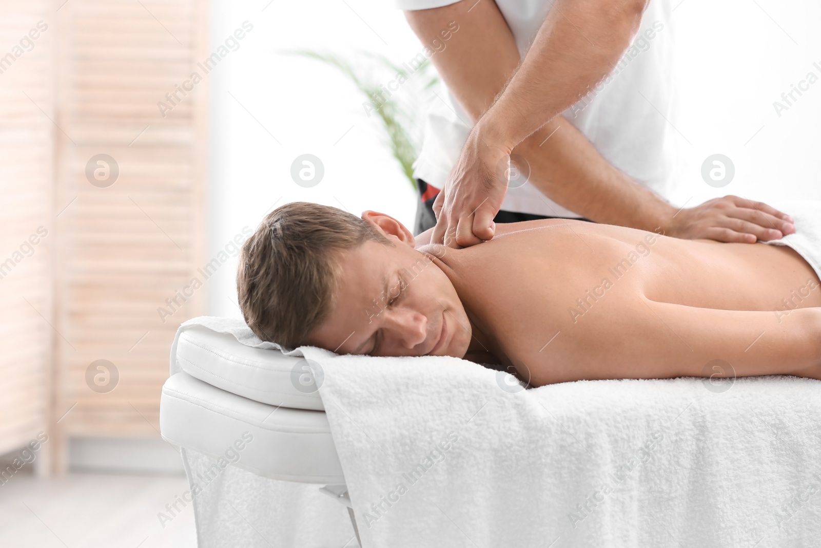 Photo of Relaxed man receiving back massage in wellness center