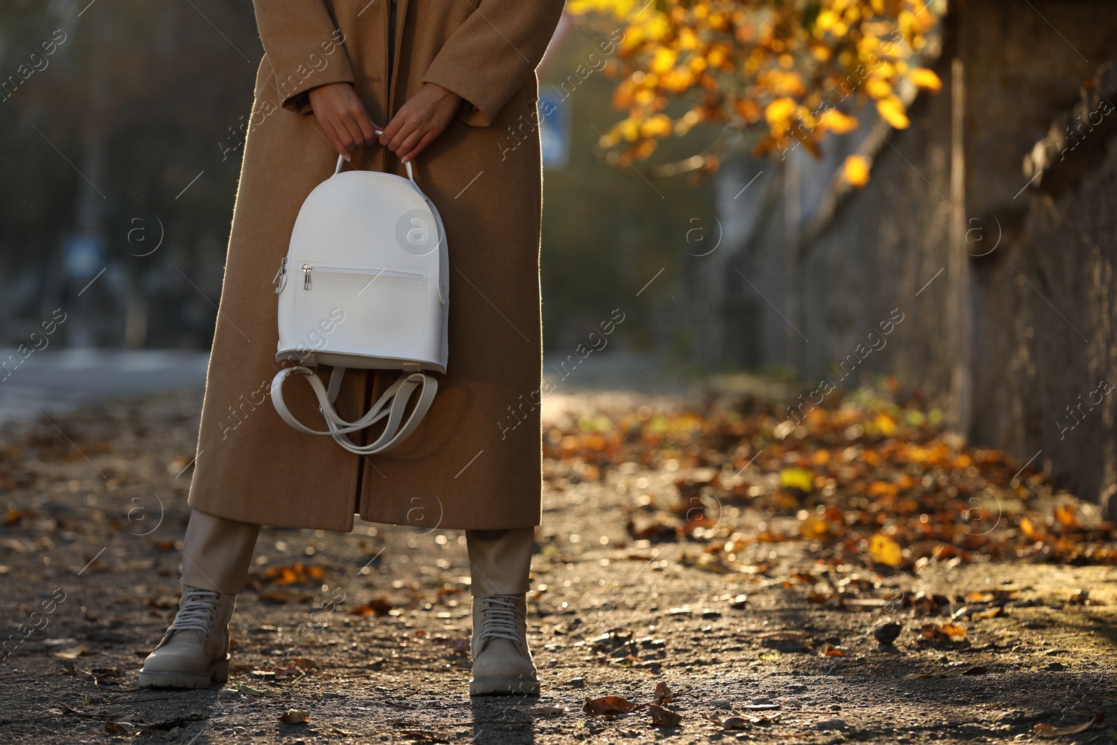 Photo of Young woman with stylish white backpack on city street, closeup. Space for text