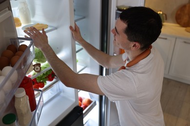 Photo of Man with sausages near refrigerator in kitchen, above view